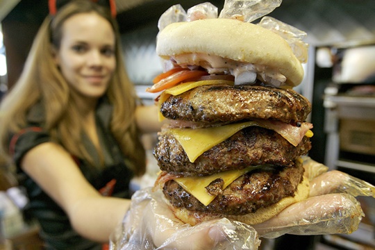 Courtney Chapman, a waitress dressed as a nurse at the Heart Attack Grill, holds up a triple bypass burger Friday, Dec. 1, 2006 in Tempe, Ariz. The waitresses at the restaurant, who wear minimal nurses attire, have angered a group of real Arizona nurses who say the servers demean their profession. (AP Photo/Matt York)